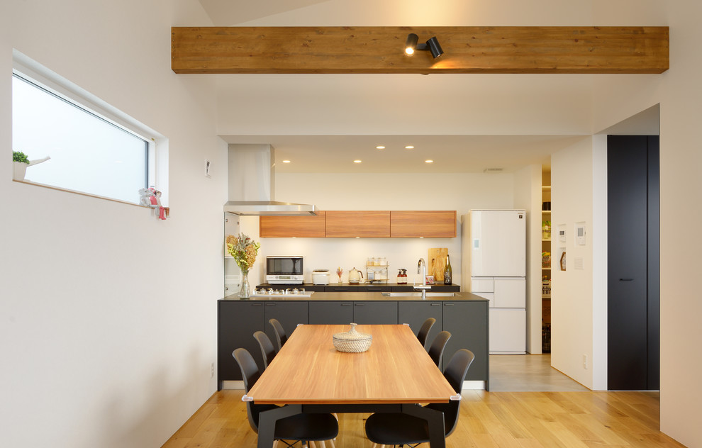 Foto på en minimalistisk matplats med öppen planlösning, med vita väggar, mellanmörkt trägolv och brunt golv