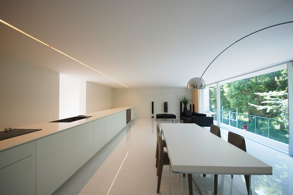 Exemple d'une salle à manger ouverte sur le salon moderne avec un mur blanc, un sol blanc et éclairage.
