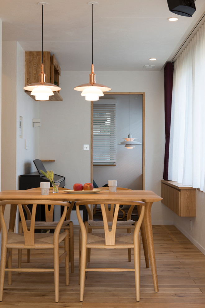 Cette photo montre une petite salle à manger scandinave avec un mur blanc et un sol en bois brun.