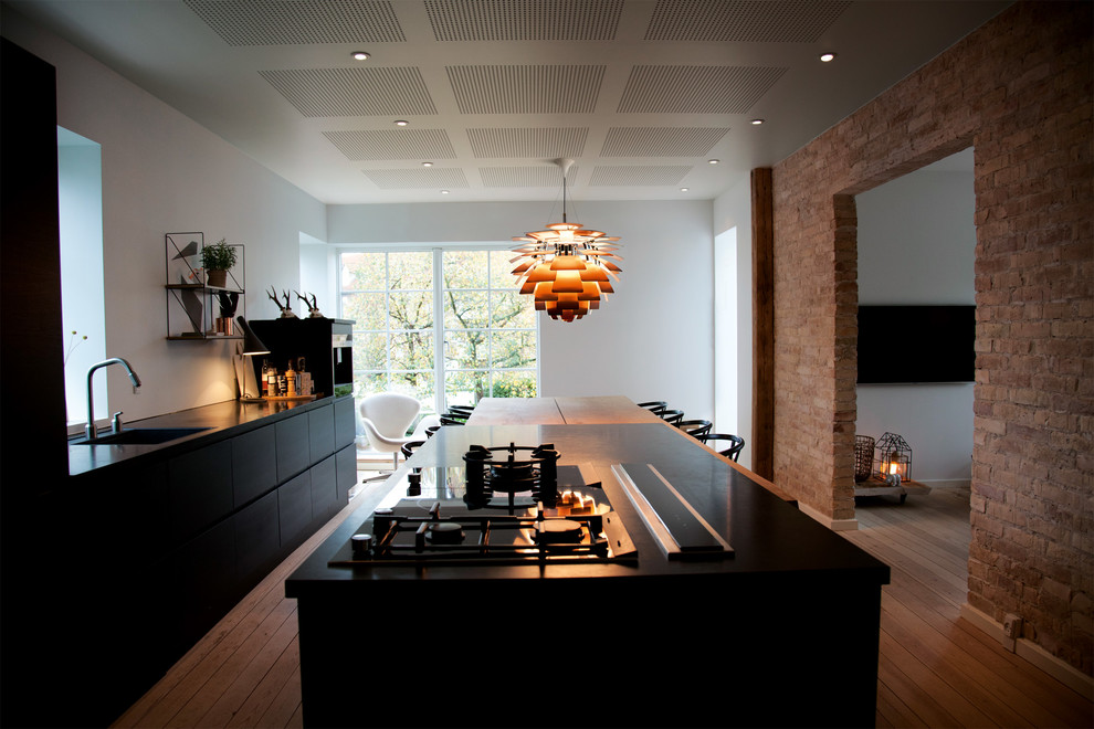 Cette image montre une salle à manger ouverte sur le salon nordique avec un mur blanc, un sol en bois brun et un sol marron.