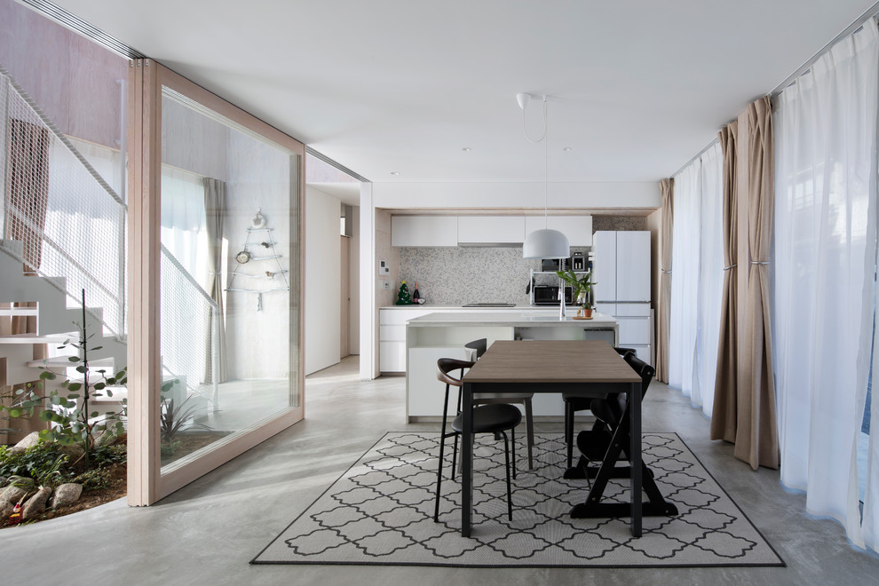 Ispirazione per una sala da pranzo aperta verso il soggiorno contemporanea con pareti bianche, pavimento in cemento e pavimento grigio