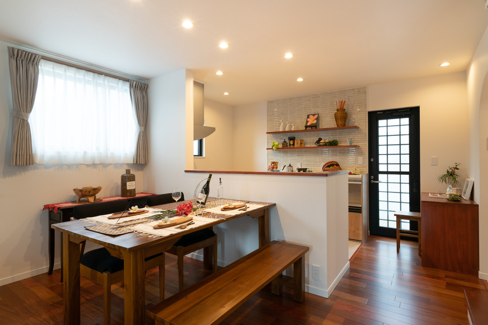 Idées déco pour une salle à manger asiatique avec un mur blanc, un sol en bois brun et un sol marron.