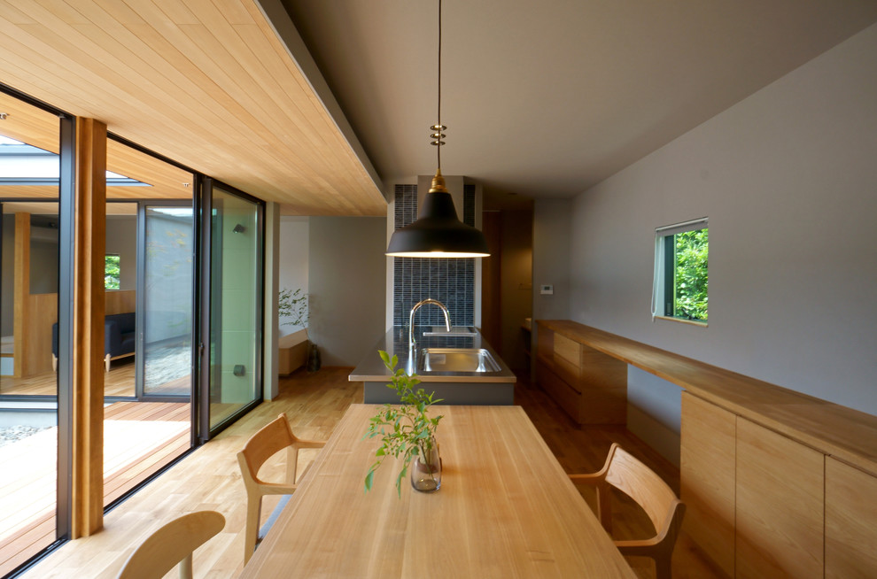 Immagine di una sala da pranzo aperta verso il soggiorno design con pareti grigie, pavimento in legno massello medio e pavimento marrone