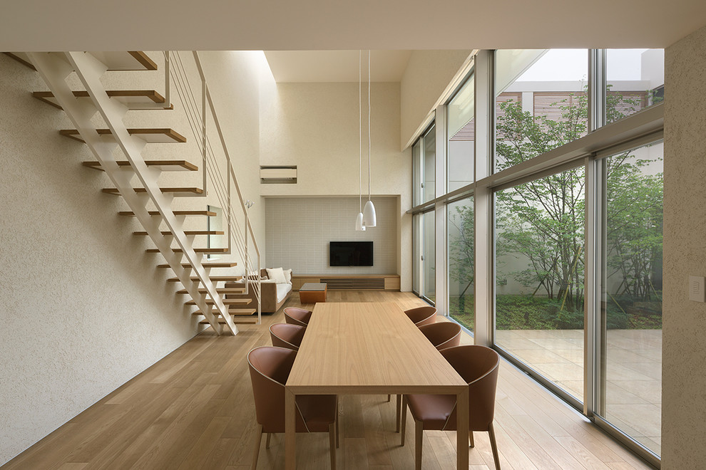 Стильный дизайн: столовая в стиле модернизм с белыми стенами, полом из фанеры и коричневым полом - последний тренд