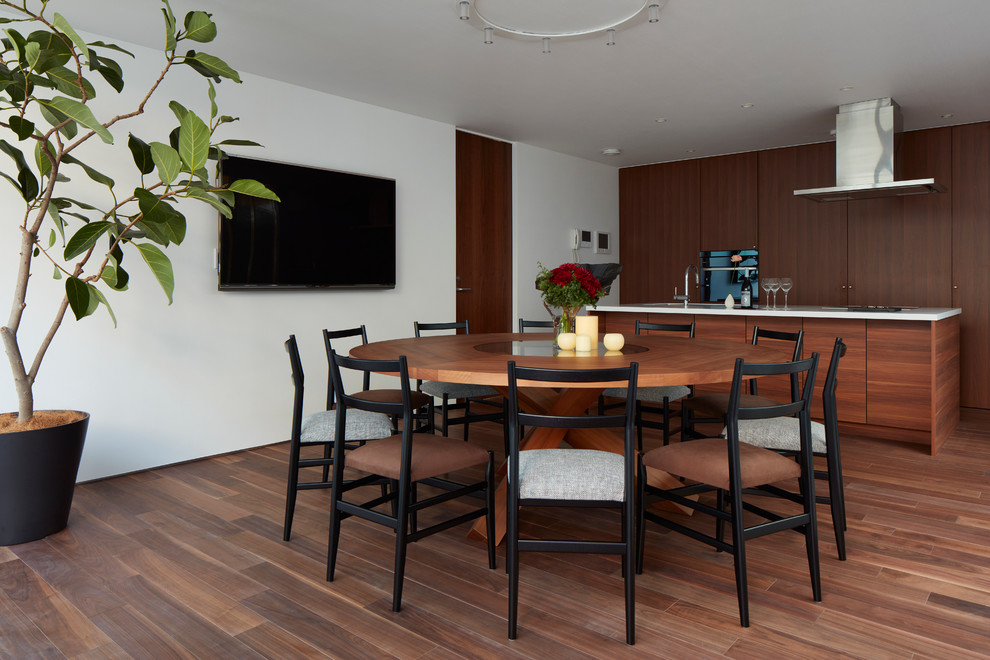 Foto di una sala da pranzo aperta verso la cucina contemporanea con pareti bianche, pavimento in legno massello medio e nessun camino