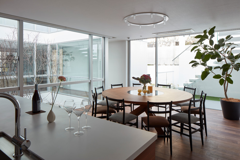Cette image montre une salle à manger ouverte sur la cuisine minimaliste de taille moyenne avec un mur blanc, parquet foncé et aucune cheminée.