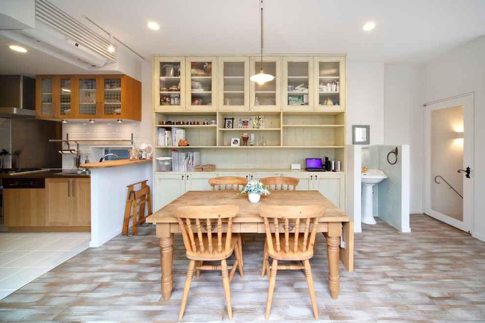 Immagine di una sala da pranzo aperta verso il soggiorno country con pareti bianche, pavimento in legno verniciato e pavimento multicolore