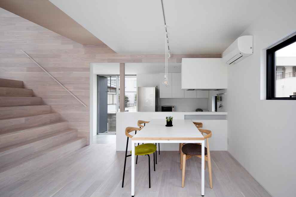 Modelo de comedor de cocina moderno con paredes blancas, suelo de madera clara y suelo beige