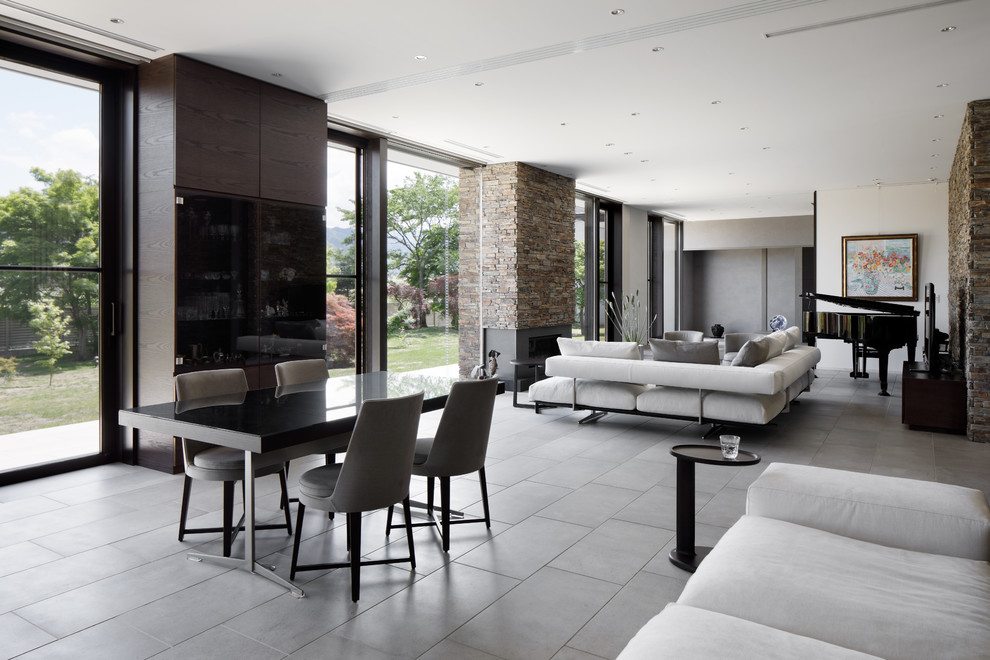 Immagine di una grande sala da pranzo aperta verso il soggiorno minimal con pareti multicolore, pavimento in cemento e pavimento grigio