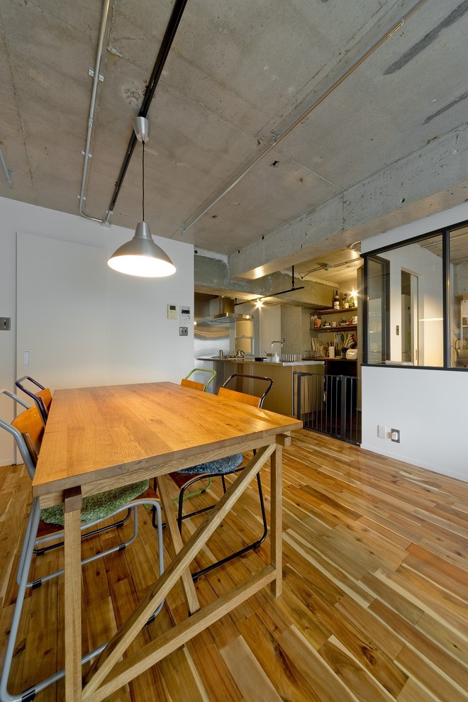 Idee per una sala da pranzo aperta verso il soggiorno industriale con pareti bianche, pavimento in legno massello medio e pavimento marrone