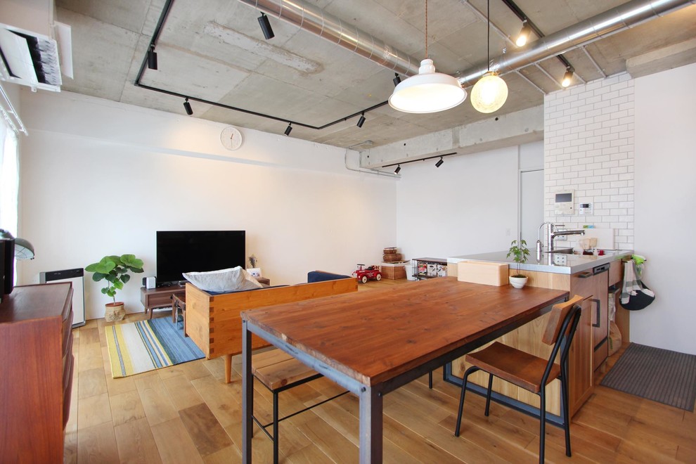 Immagine di una sala da pranzo aperta verso il soggiorno industriale con pareti bianche, pavimento in legno massello medio e pavimento marrone