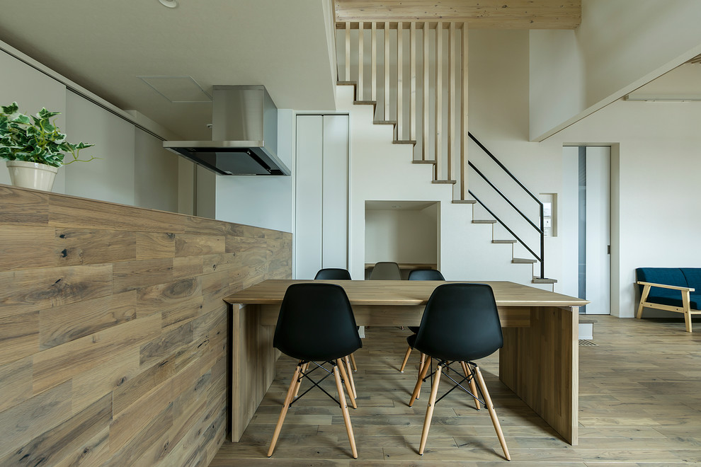 На фото: гостиная-столовая в стиле модернизм с белыми стенами, деревянным полом и коричневым полом с