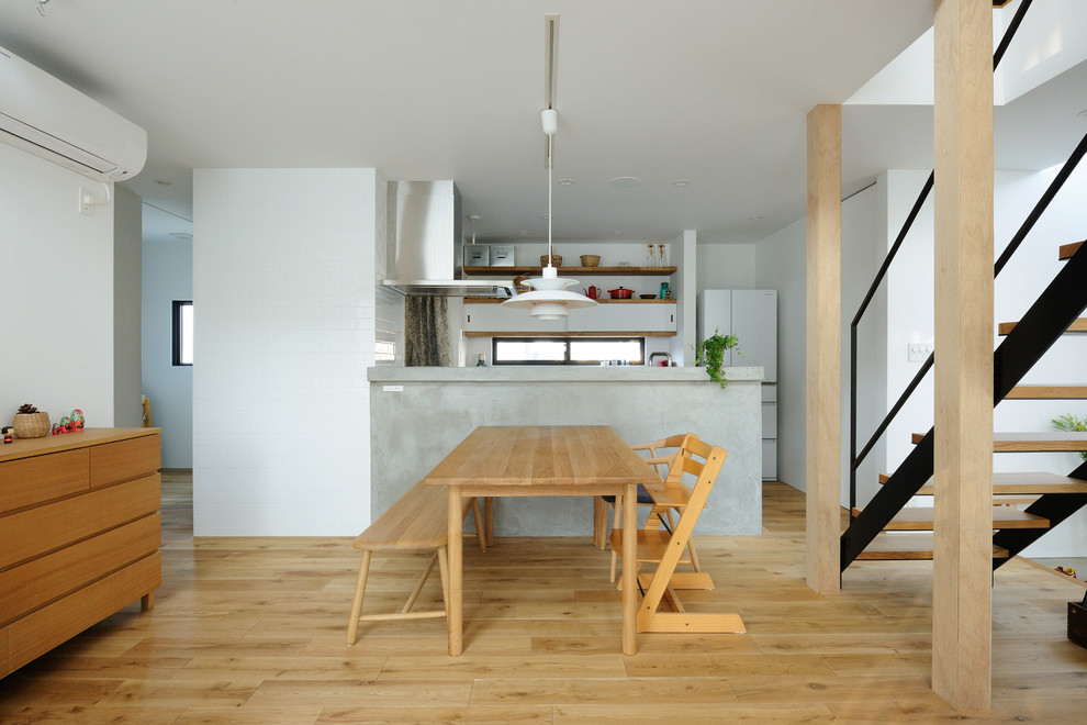 Immagine di una sala da pranzo aperta verso la cucina etnica con pareti bianche, parquet chiaro e pavimento marrone