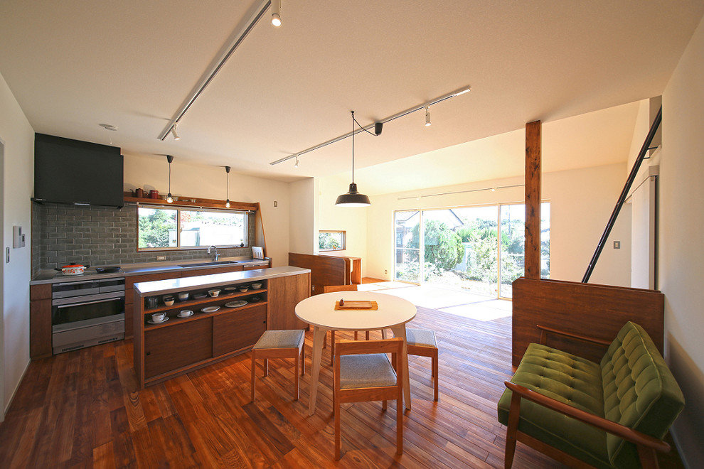 Idee per una sala da pranzo aperta verso il soggiorno etnica con pareti bianche, pavimento in legno massello medio e pavimento marrone