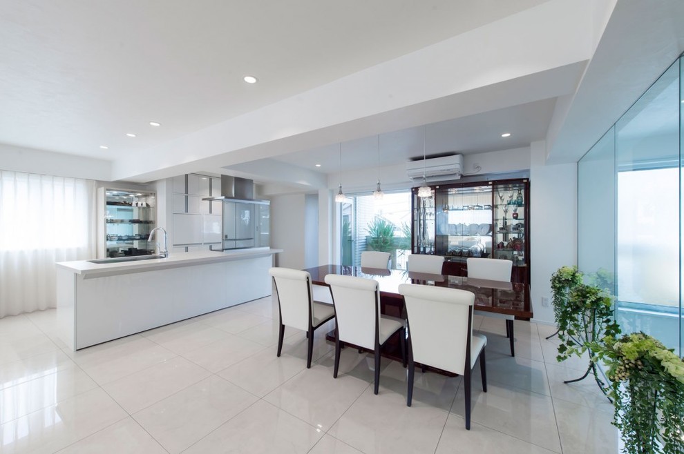Cette image montre une salle à manger ouverte sur le salon minimaliste avec un mur blanc et un sol blanc.