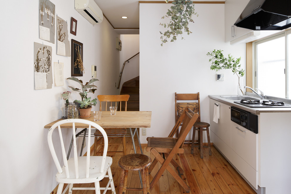 Idées déco pour une petite salle à manger ouverte sur la cuisine campagne avec un mur blanc, un sol en bois brun, un sol marron et éclairage.
