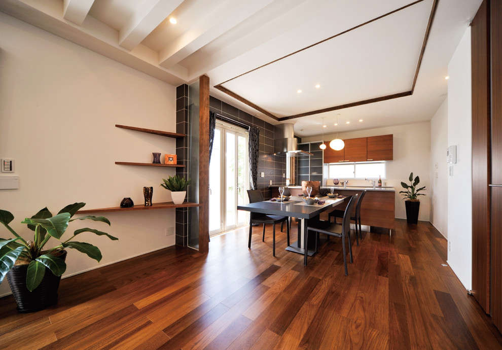 Foto di una sala da pranzo aperta verso il soggiorno minimal con pareti bianche, pavimento in legno massello medio e pavimento marrone