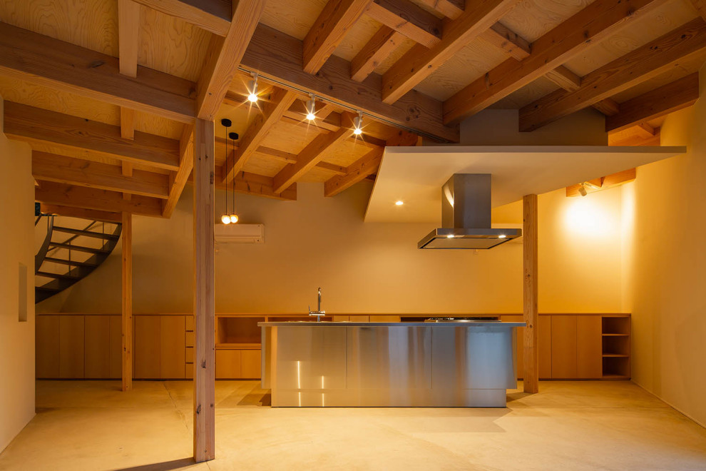Ejemplo de comedor de estilo zen pequeño abierto con paredes blancas, suelo de cemento, estufa de leña, marco de chimenea de hormigón, suelo gris y vigas vistas