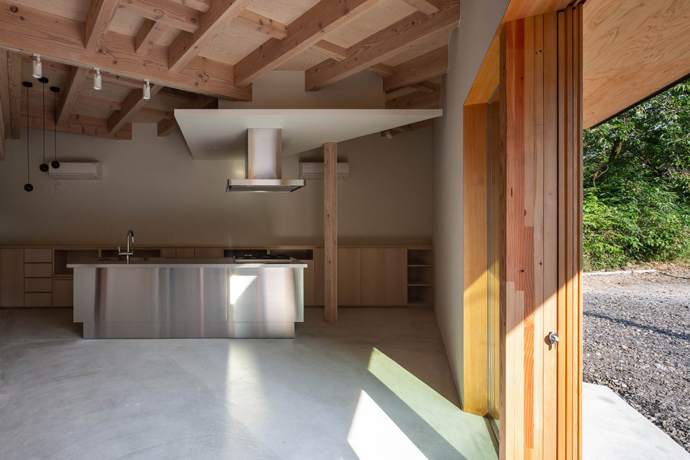 Ejemplo de comedor de estilo zen pequeño abierto con paredes blancas, suelo de cemento, estufa de leña, marco de chimenea de hormigón, suelo gris y vigas vistas