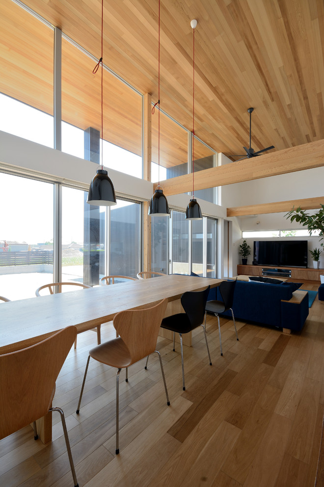 Esempio di una sala da pranzo aperta verso il soggiorno moderna con pareti bianche, pavimento in legno massello medio e pavimento marrone