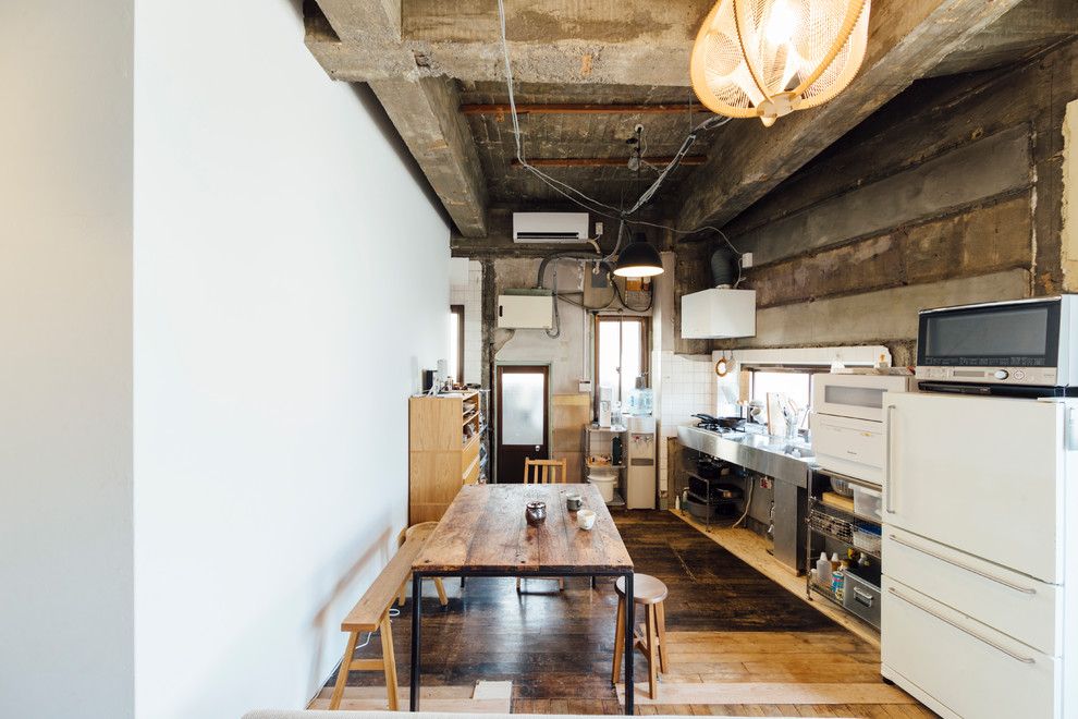 Ispirazione per una sala da pranzo aperta verso la cucina industriale con pareti bianche, parquet scuro e pavimento marrone