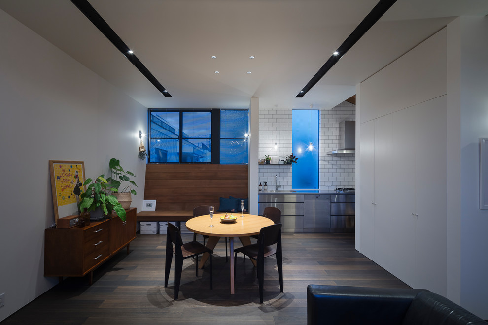 Esempio di una sala da pranzo aperta verso il soggiorno industriale con pareti bianche, pavimento in legno verniciato e pavimento grigio