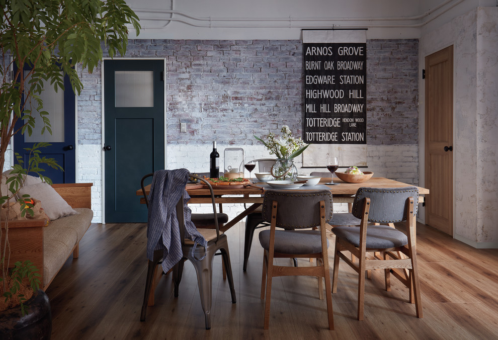 Foto di una sala da pranzo industriale con pareti bianche, pavimento in legno massello medio e pavimento marrone
