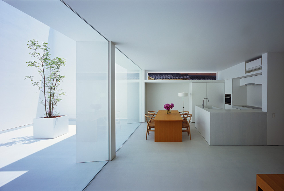 Imagen de comedor de cocina moderno sin chimenea con paredes blancas y suelo de cemento
