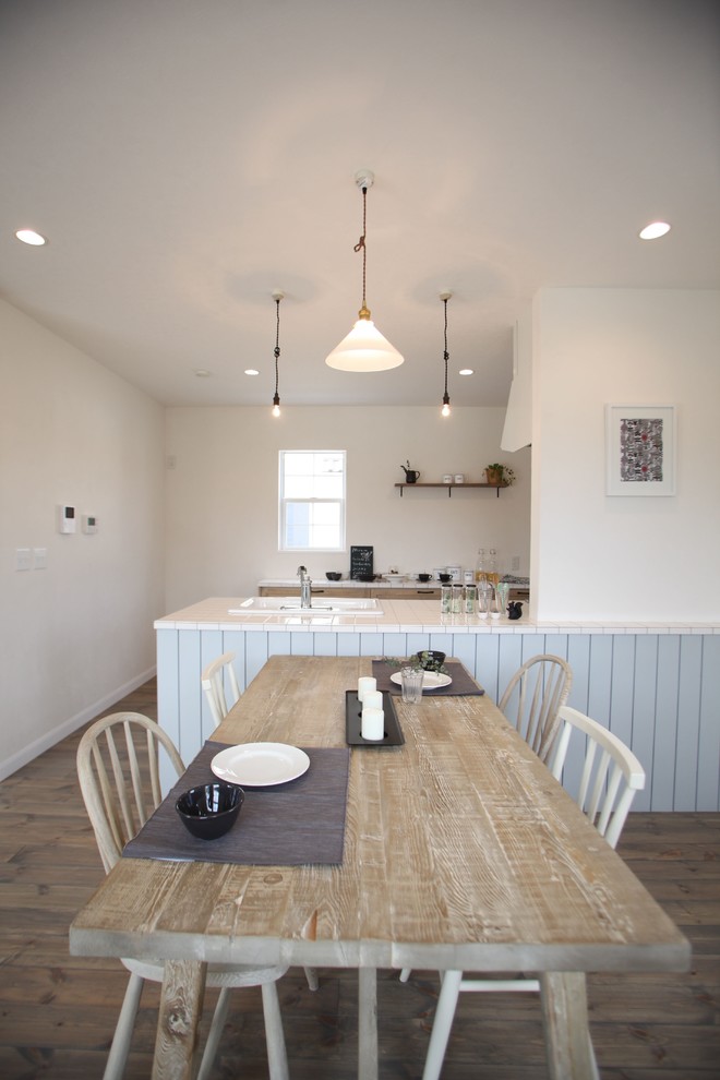 Idées déco pour une salle à manger ouverte sur le salon bord de mer avec un mur blanc, un sol en bois brun et un sol marron.