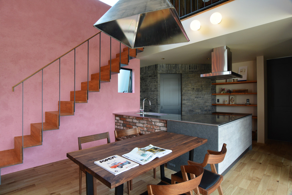 Cette photo montre une salle à manger ouverte sur le salon asiatique avec un mur rose, un sol en bois brun et un sol marron.