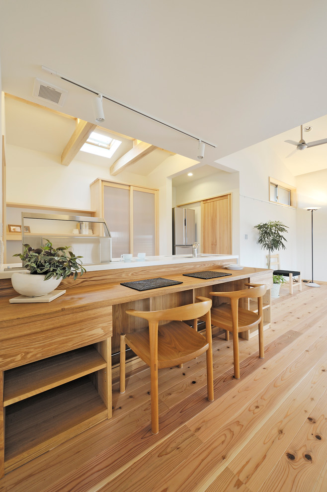 Foto di una sala da pranzo aperta verso il soggiorno etnica con pareti bianche, pavimento in legno massello medio e pavimento marrone