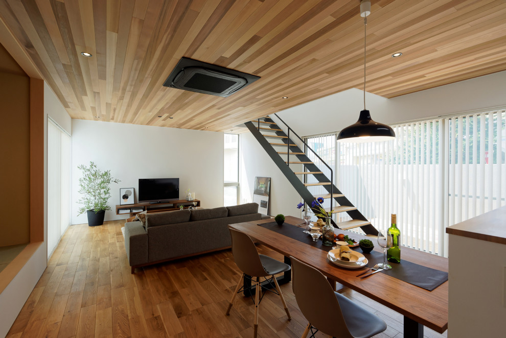 Imagen de comedor minimalista abierto sin chimenea con paredes blancas y suelo de madera en tonos medios