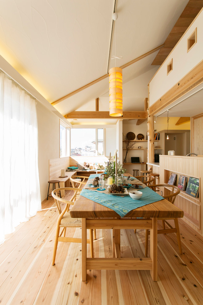 Cette image montre une salle à manger ouverte sur le salon asiatique avec un mur blanc, un sol en bois brun et un sol marron.