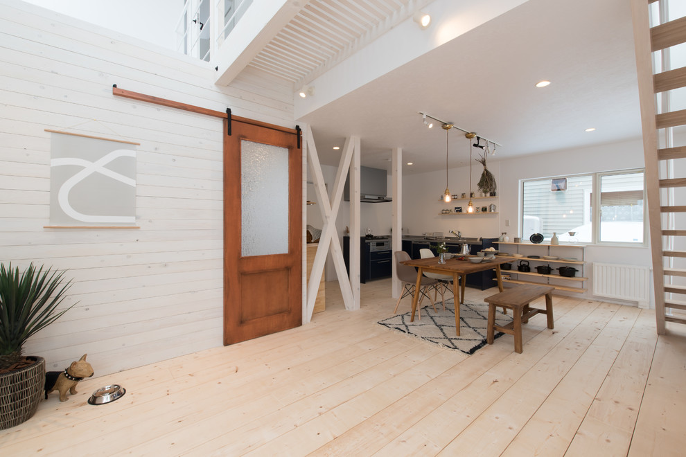 Idée de décoration pour une salle à manger ouverte sur le salon champêtre avec un mur blanc, parquet clair et un sol marron.