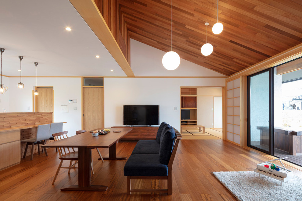 Immagine di una sala da pranzo aperta verso il soggiorno etnica con pareti bianche, pavimento marrone e pavimento in legno massello medio