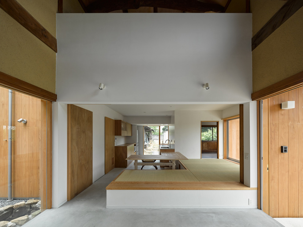 Стильный дизайн: гостиная-столовая среднего размера в классическом стиле с белыми стенами, бетонным полом, серым полом, балками на потолке, печью-буржуйкой и фасадом камина из бетона - последний тренд
