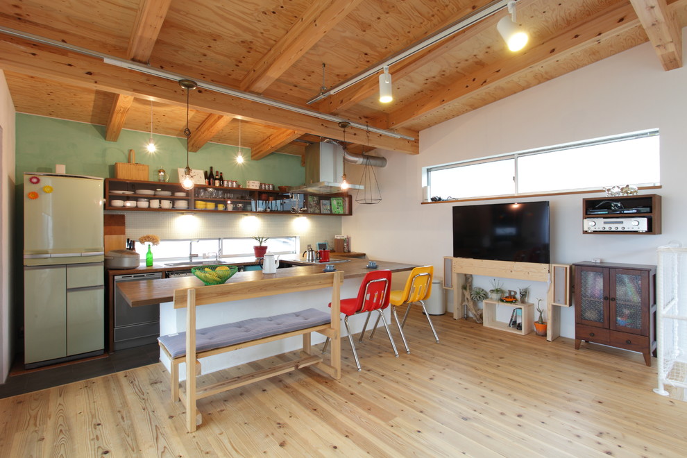 Idee per una sala da pranzo aperta verso il soggiorno etnica con parquet chiaro, pavimento marrone e pareti verdi
