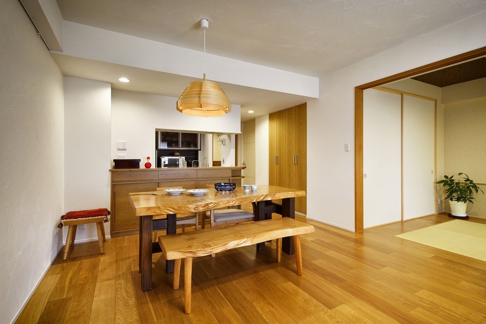 Medium sized world-inspired open plan dining room with white walls, medium hardwood flooring and brown floors.