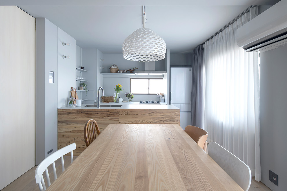 Diseño de comedor nórdico abierto con suelo de madera clara y suelo beige