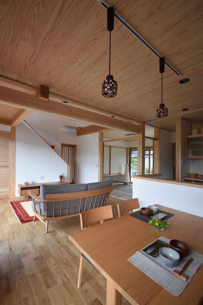 Foto de comedor de estilo zen abierto con paredes blancas, suelo de madera clara y suelo marrón