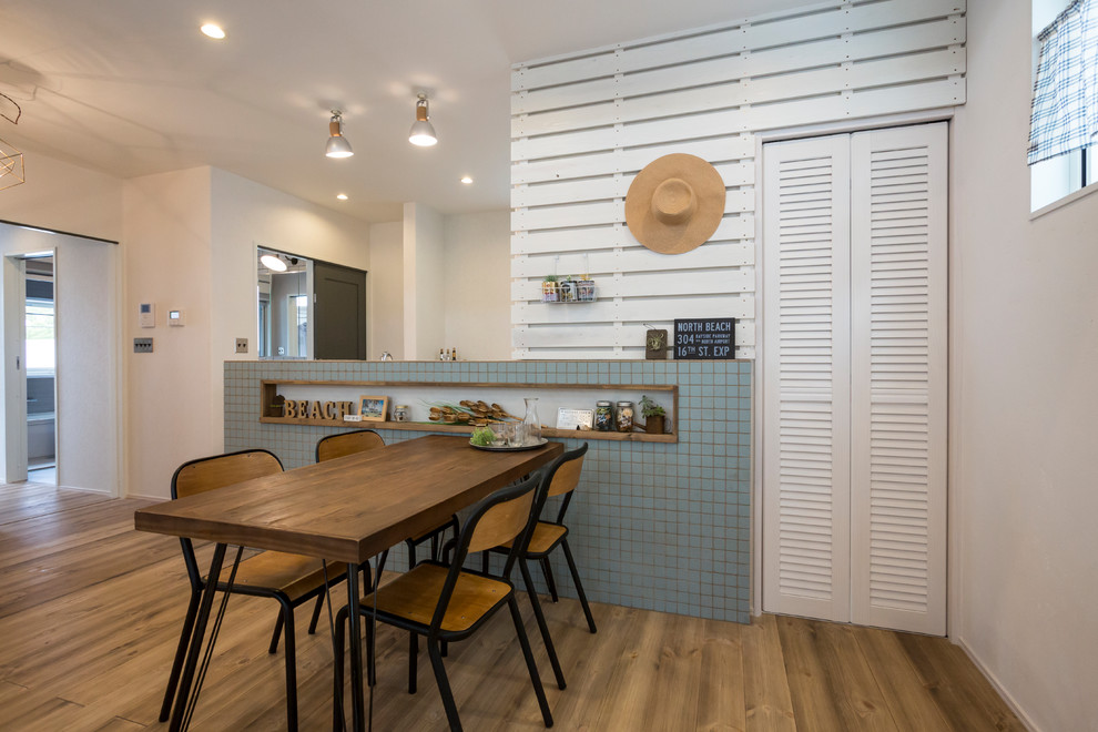 Idee per una sala da pranzo costiera con pareti bianche, pavimento in legno massello medio e pavimento marrone