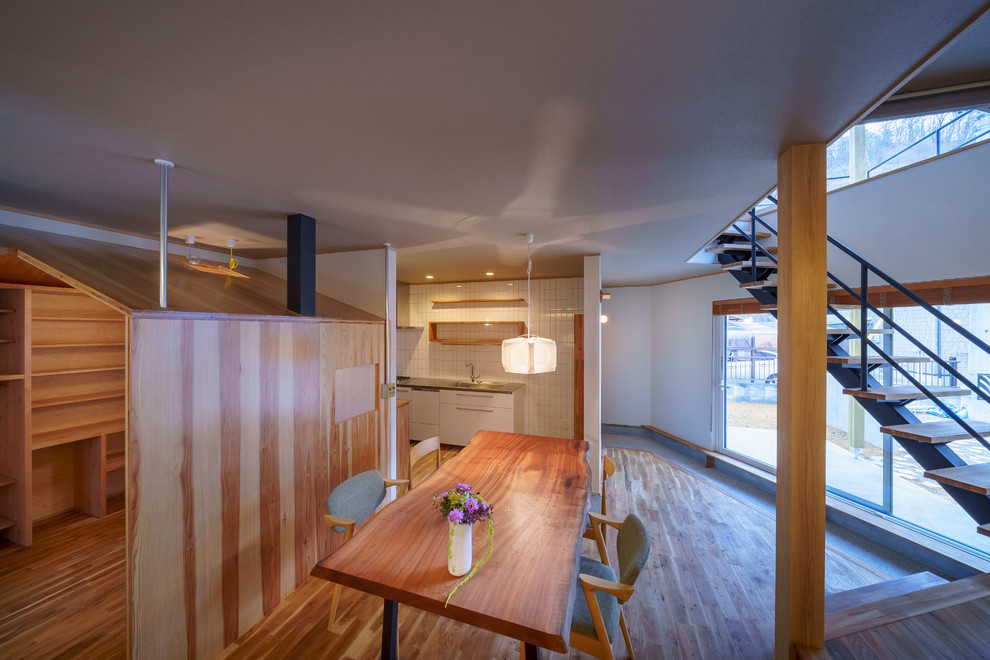 Ispirazione per una sala da pranzo minimal con pareti bianche, pavimento in legno massello medio e pavimento marrone