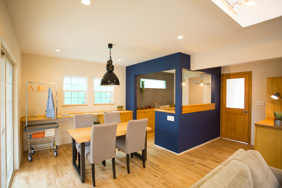 Immagine di una sala da pranzo aperta verso il soggiorno minimalista di medie dimensioni con pareti bianche, pavimento in legno massello medio e pavimento marrone