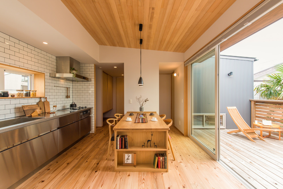 Foto di una sala da pranzo aperta verso il soggiorno etnica con pareti bianche, pavimento in legno massello medio e pavimento marrone