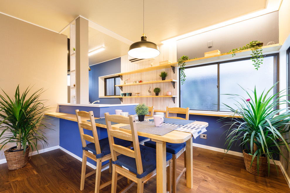 Cette image montre une petite salle à manger nordique avec un mur bleu, parquet foncé, aucune cheminée et un sol marron.