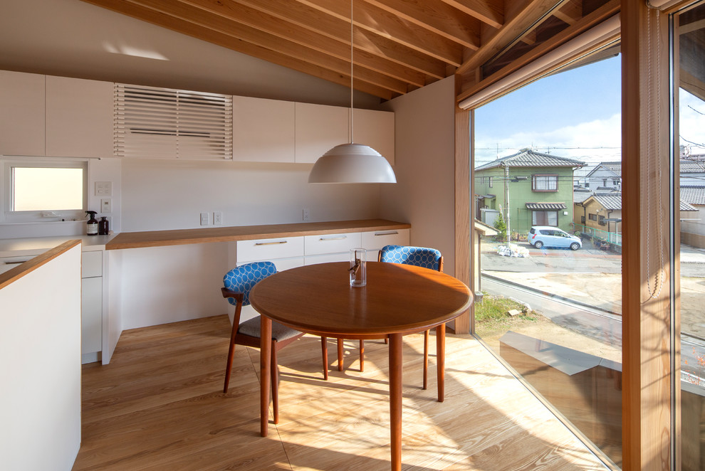 Imagen de comedor de estilo zen con paredes blancas, suelo de madera clara y suelo marrón