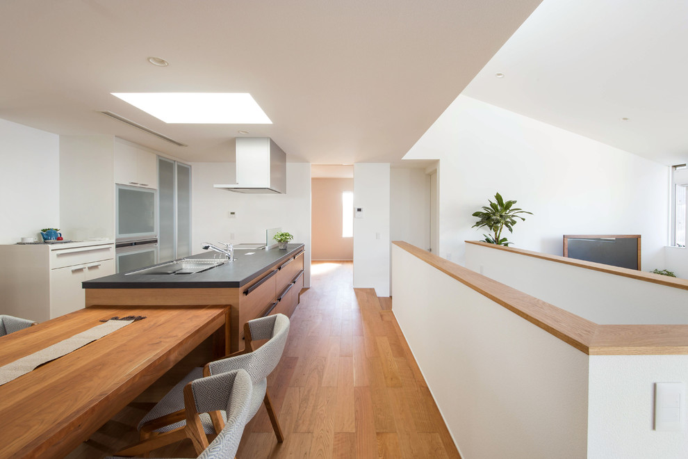 Idées déco pour une salle à manger ouverte sur la cuisine moderne avec un sol en contreplaqué et un sol marron.