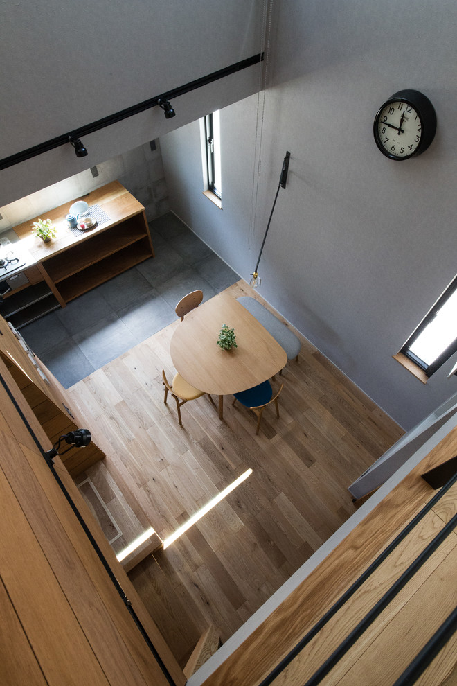 Ispirazione per una sala da pranzo aperta verso il soggiorno industriale con pareti grigie e pavimento in legno massello medio