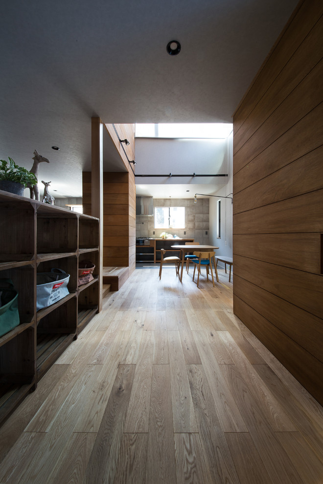 Foto di una sala da pranzo aperta verso la cucina industriale con pareti grigie e pavimento in legno massello medio