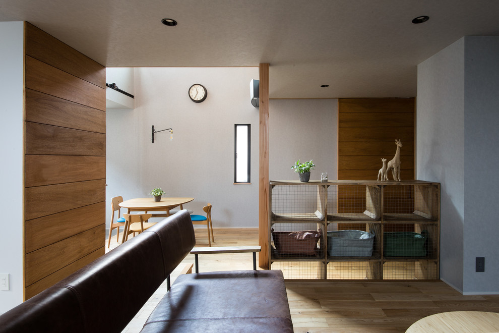 Immagine di una sala da pranzo aperta verso la cucina industriale con pareti grigie e pavimento in legno massello medio